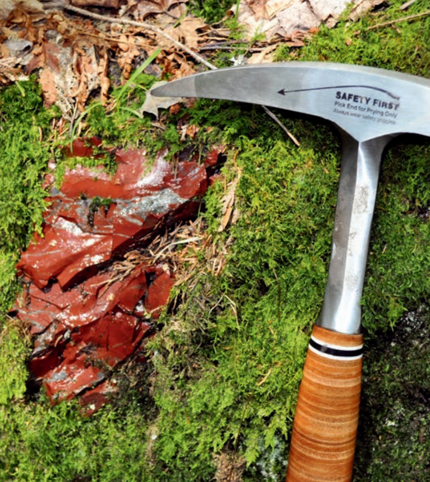 A pickaxe resting next to a red munsungun chert quarry face